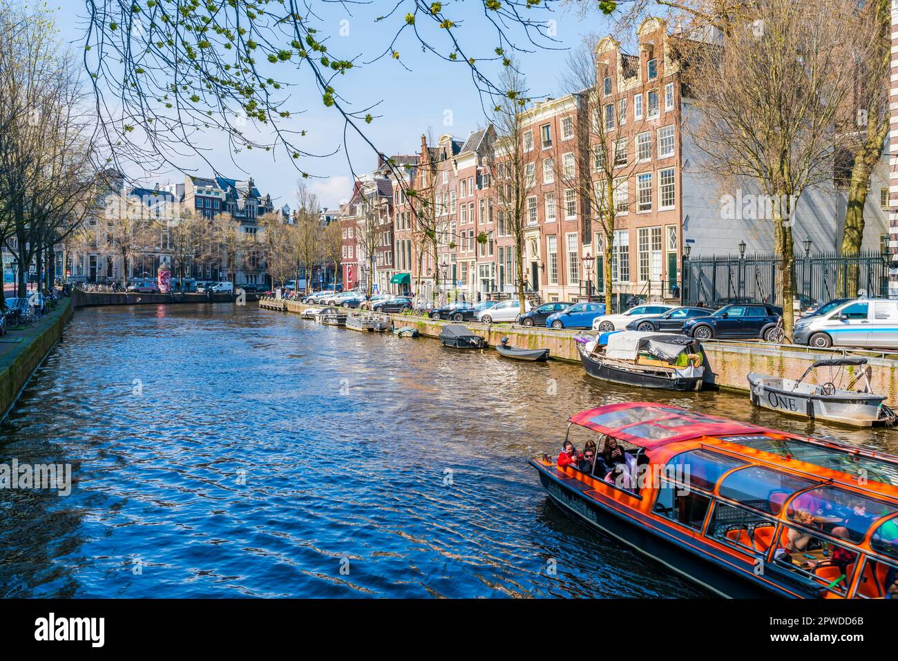 AMSTERDAM, HOLLAND - 17. APRIL 2023: Touristen genießen eine Bootsfahrt entlang eines Kanals in Amsterdam, niederländische Hauptstadt Stockfoto