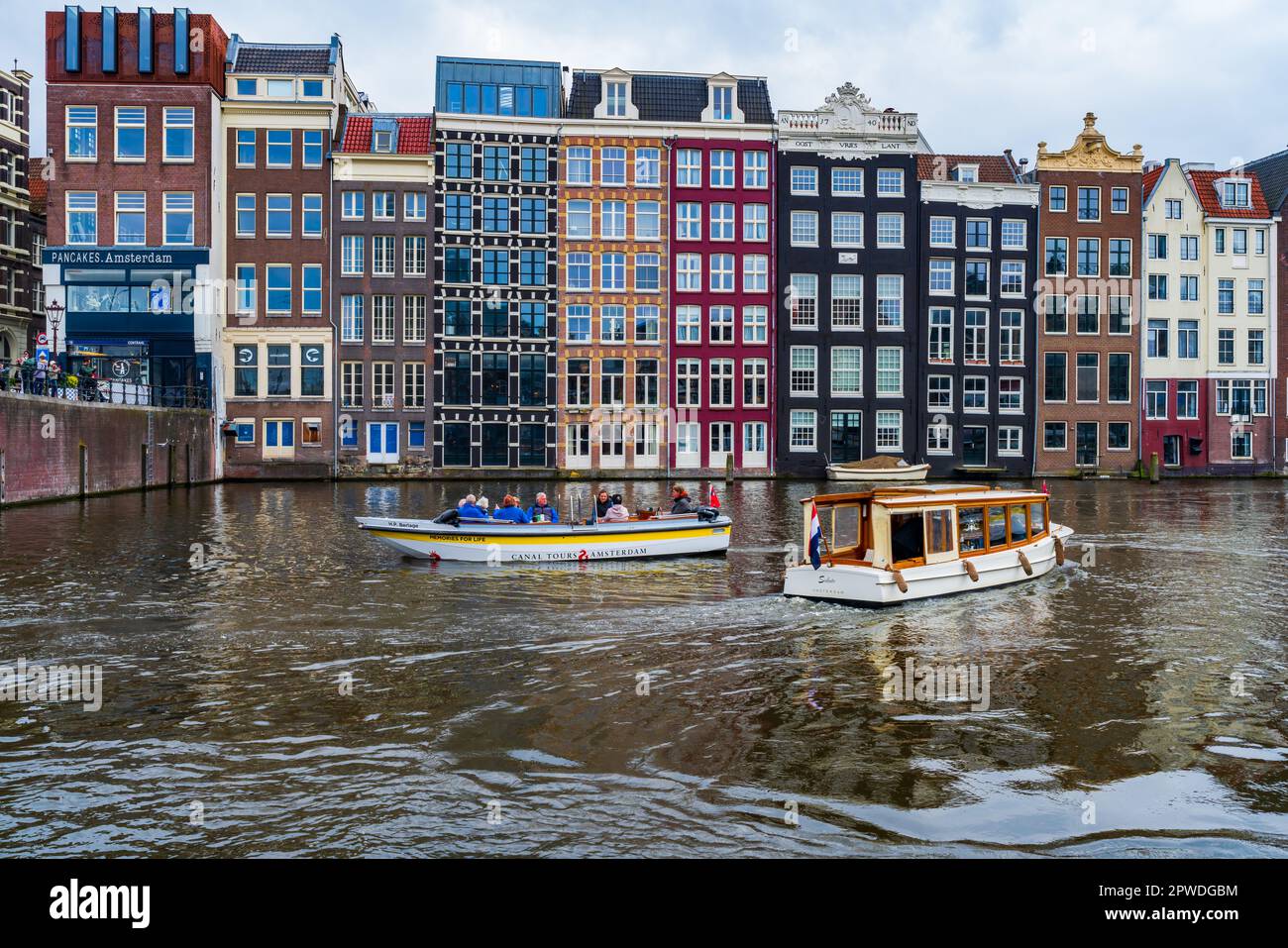 AMSTERDAM, HOLLAND - 17. APRIL 2023: Touristen auf Kreuzfahrtschiffen machen eine Fahrt entlang der Kanäle in der niederländischen Hauptstadt, die für ihr aufwändiges Kanalsystem bekannt ist Stockfoto