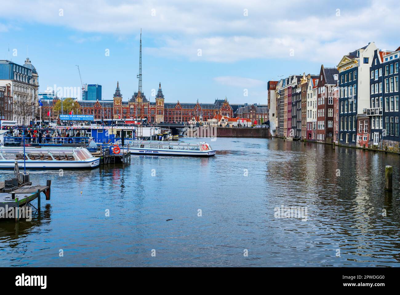 AMSTERDAM, HOLLAND - APRIL 18 2023: Touristen gehen an Bord von Kreuzfahrtschiffen und machen eine Fahrt entlang der Kanäle in der niederländischen Hauptstadt, die für ihr aufwändiges Kanalsystem bekannt ist Stockfoto