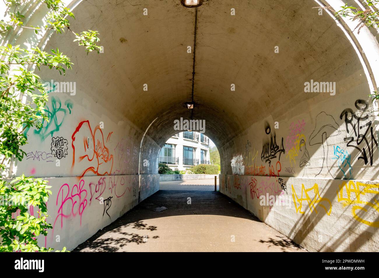 Eine Leitung führt durch einen Tunnel unter der Lesebrücke. Die Tunnelwände sind mit Grafitti bedeckt. Stockfoto