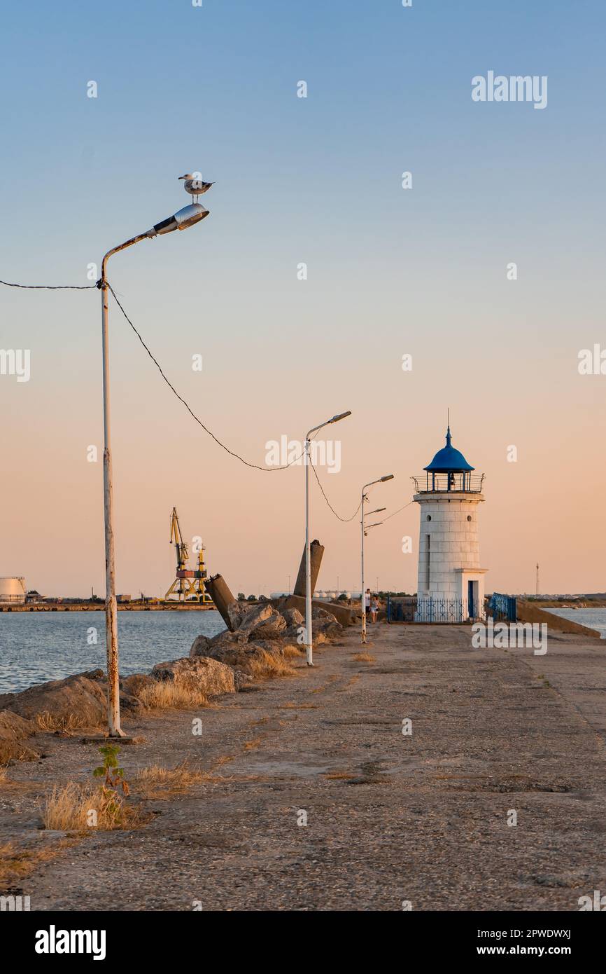 Aus nächster Nähe sehen Sie den Leuchtturm von Genua mit einem blauen Dach, vom Pier aus Felsen, in einem Hafen am Schwarzen Meer. Stockfoto