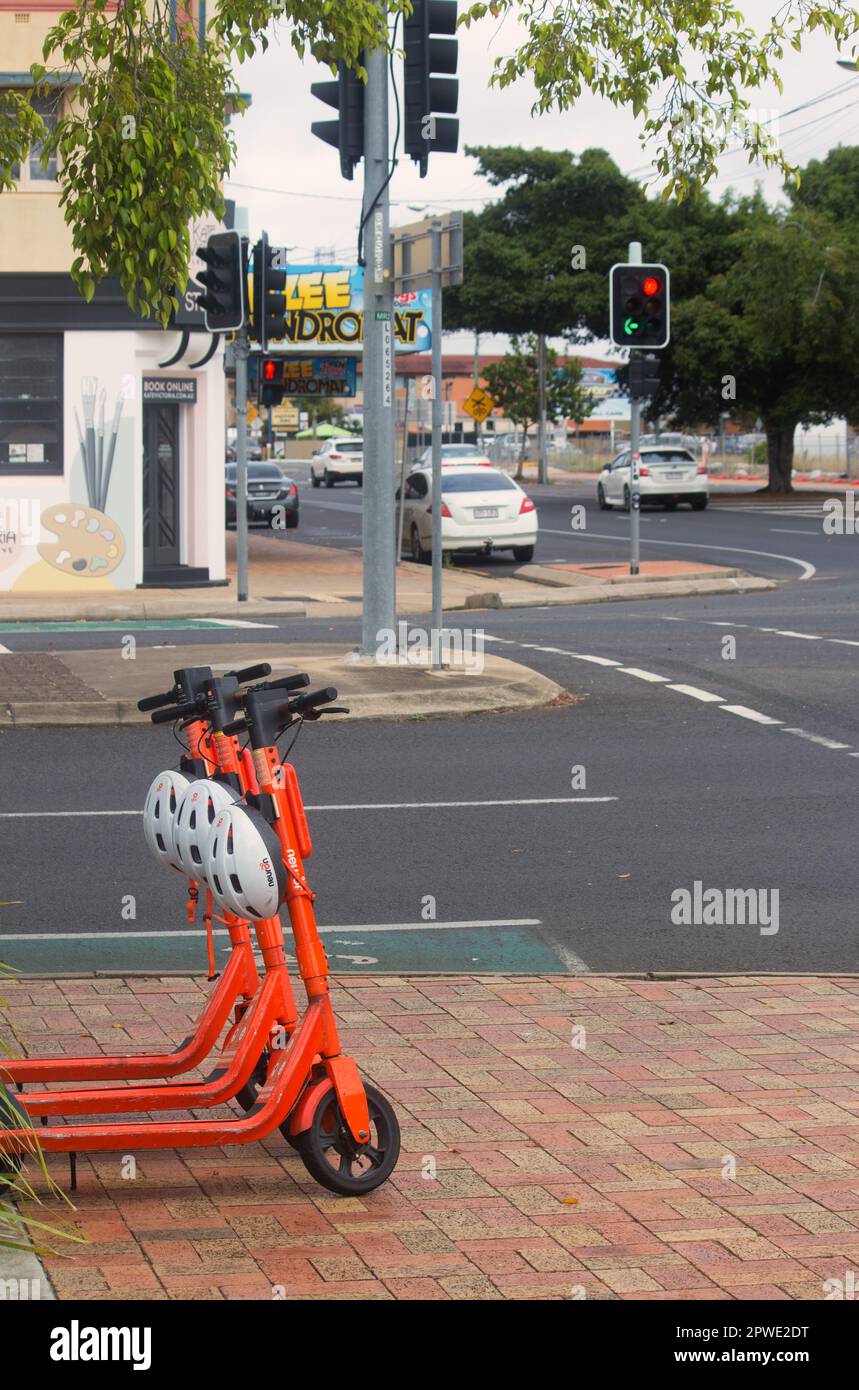 Bundaberg, Queensland, Australien, Oktober 10. 2022. E-Scooter mit Helmen, die auf einem Fußweg in der Stadt zur elektronischen Ausleihe bereitstehen. Stockfoto