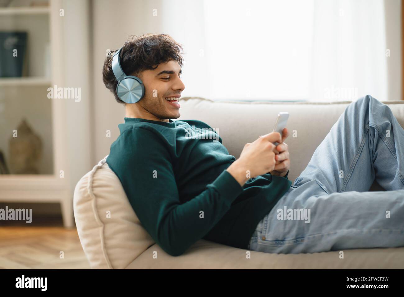 Seitenansicht Des Mannes Mit Smartphone Mit Kopfhörern Zu Hause Stockfoto