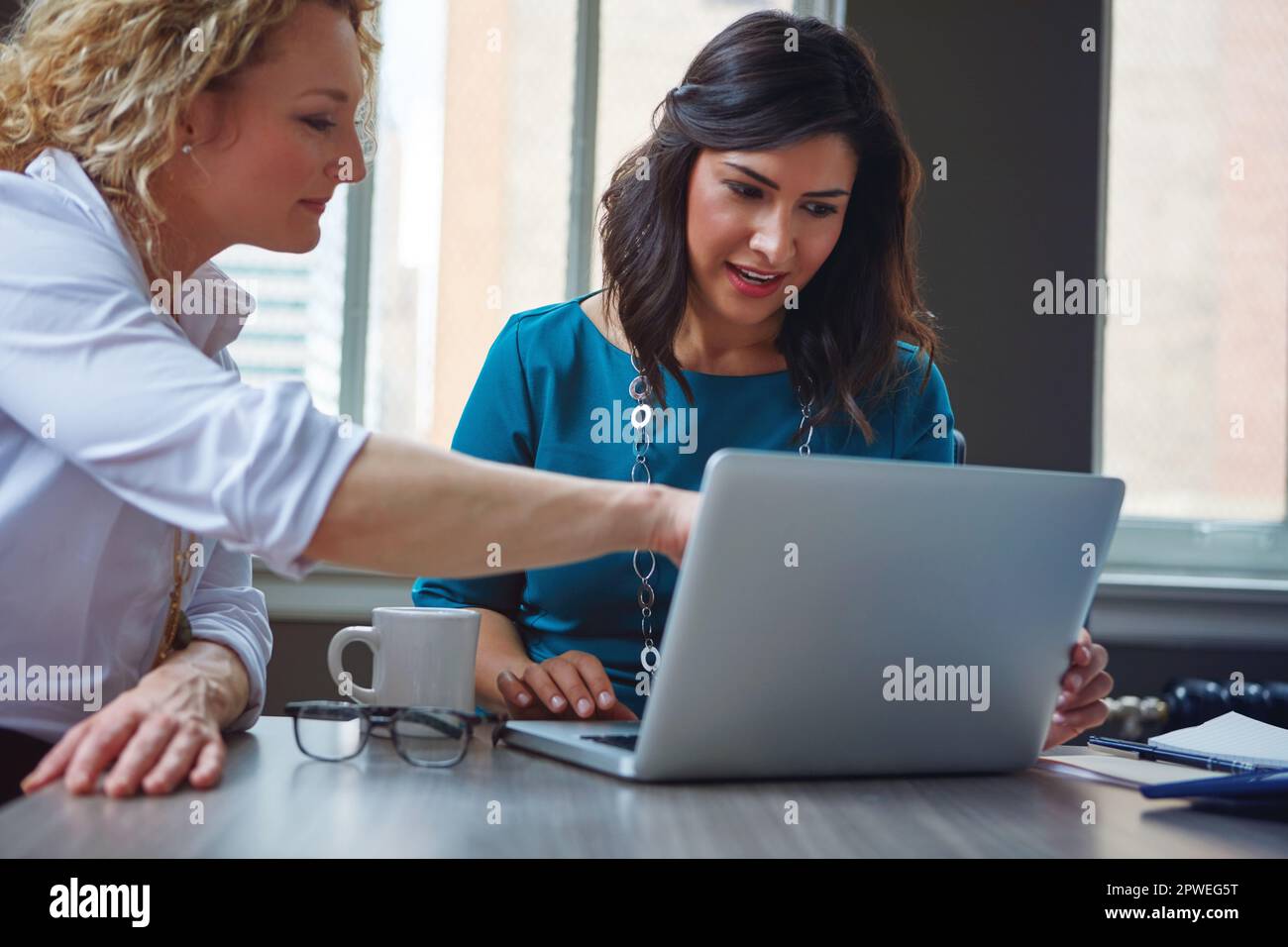 Dank Online-Recherche sind sie der Konkurrenz immer einen Schritt voraus. Zwei Geschäftsfrauen, die zusammen ein Notebook in einem Büro benutzen. Stockfoto