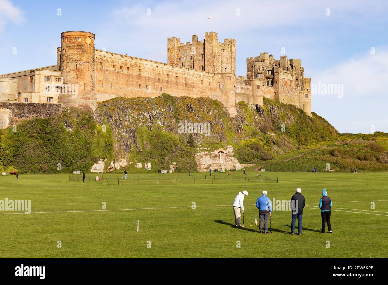 Bamburgh Castle Northumberland UK; der lokale Club, der Krocket auf dem Grün vor dem Schloss spielt; Bamburgh Village, Northumberland UK Stockfoto