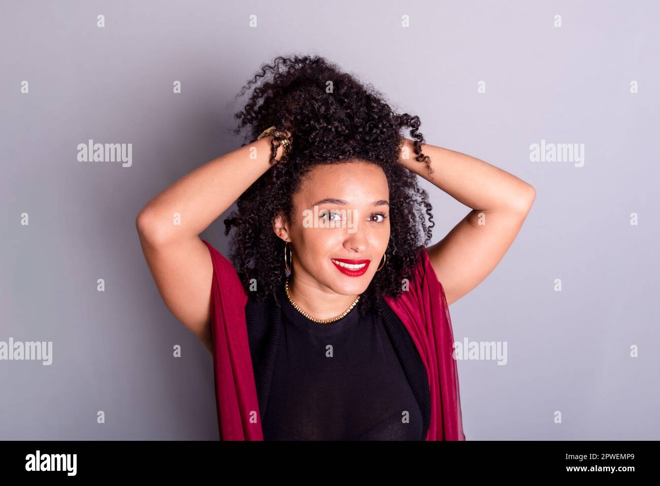 Schöne junge Frau, die ihr Haar mit einem roten Tuch berührte. studioporträt Stockfoto