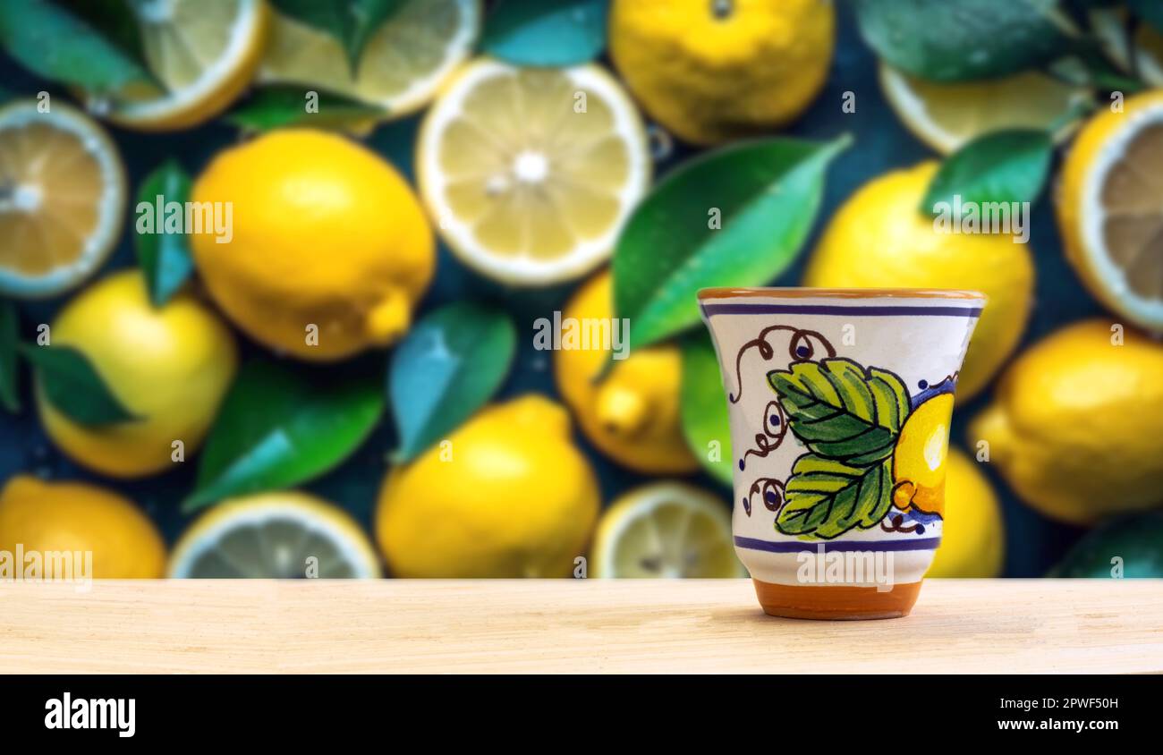 Traditioneller hausgemachter Zitronenlikör Limoncello und frische Zitrusfrüchte, selektiver Fokus auf ein Zitronenfeld im Hintergrund an einem sonnigen Tag. Vorderansicht. Horizontal Stockfoto
