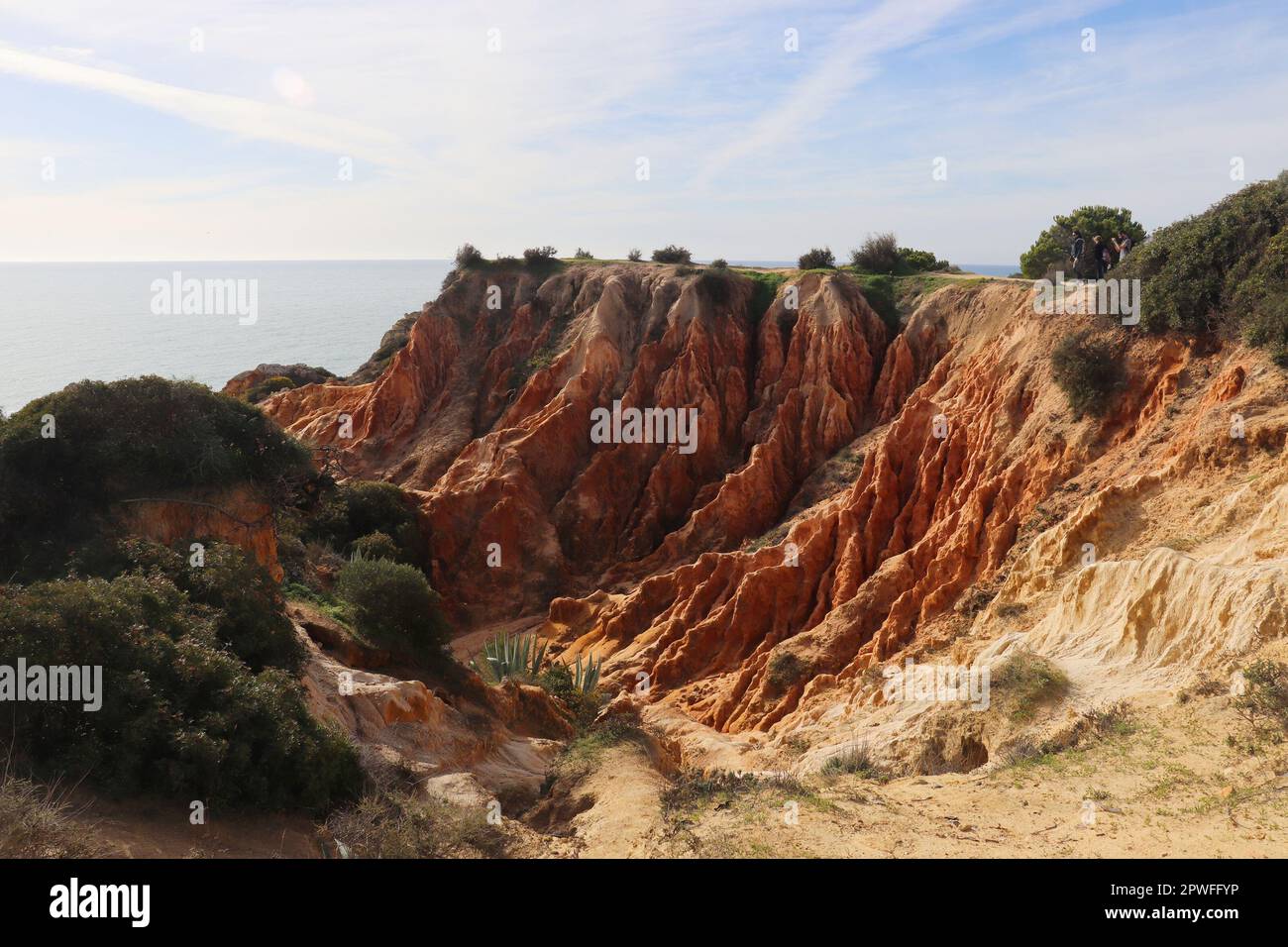 Orangefarbene Kalksteinklippen neben dem Atlantischen Ozean auf dem Wanderweg Seven Hanging Valley in der Algarve, Portugal. Stockfoto