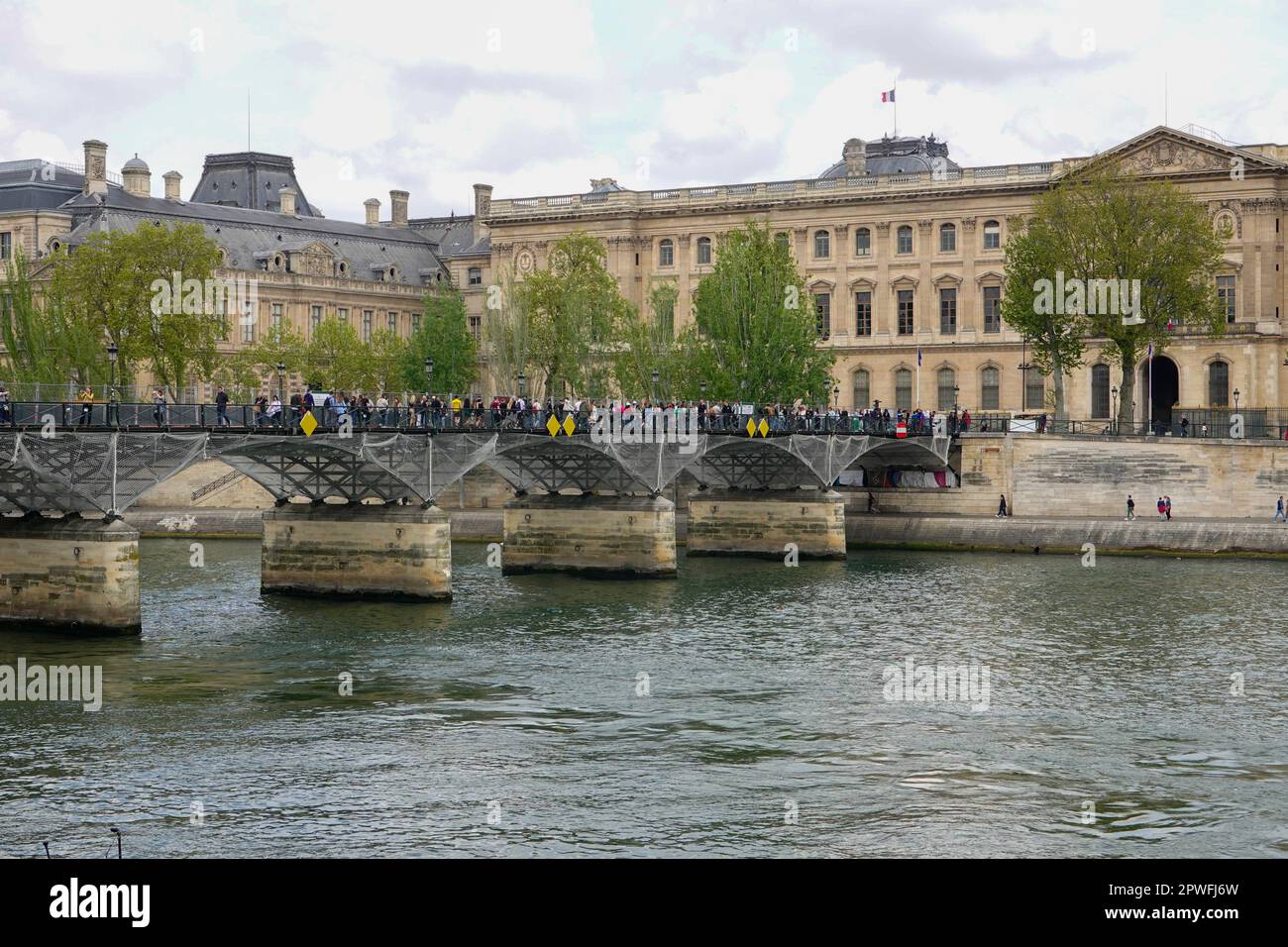 Menschen an der Pont des Arts oder Passerelle des Arts, einer Fußgängerbrücke über die seine, mit Blick auf den Louvre, Paris, FR. Stockfoto