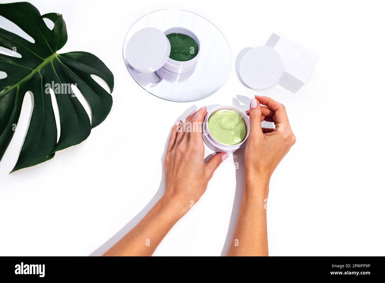 Nahaufnahme gut gepflegter weiblicher Hände mit wunderschöner Maniküre-Aufbewahrungsbox mit grünen Flecken. Kastenmodelle, Spiegel und Monsterablage auf isoliertem Weiß Stockfoto
