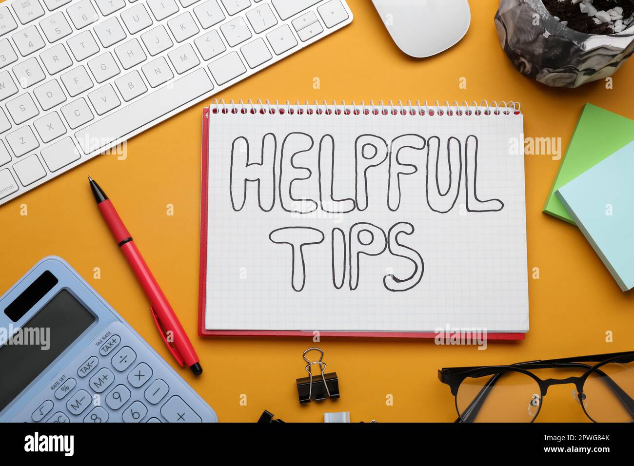 Hilfreiche Tipps. Flache Verlegung mit Notebook, Taschenrechner und Computertastatur auf orangefarbenem Hintergrund Stockfoto
