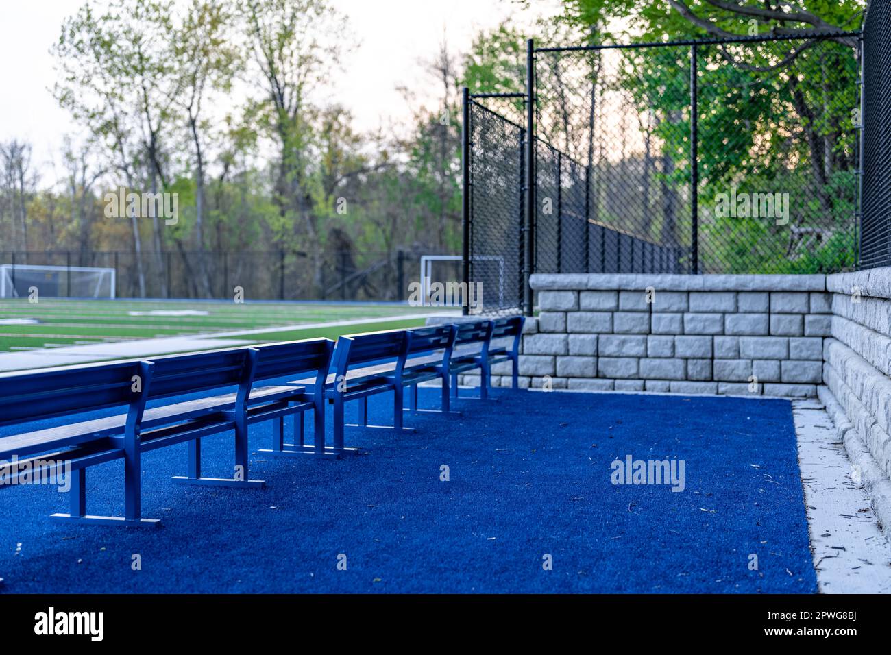 Am späten Nachmittag Foto eines blauen Sitzes oder einer Bank mit Kunstrasenfeld und Haltewand im Hintergrund. Stockfoto