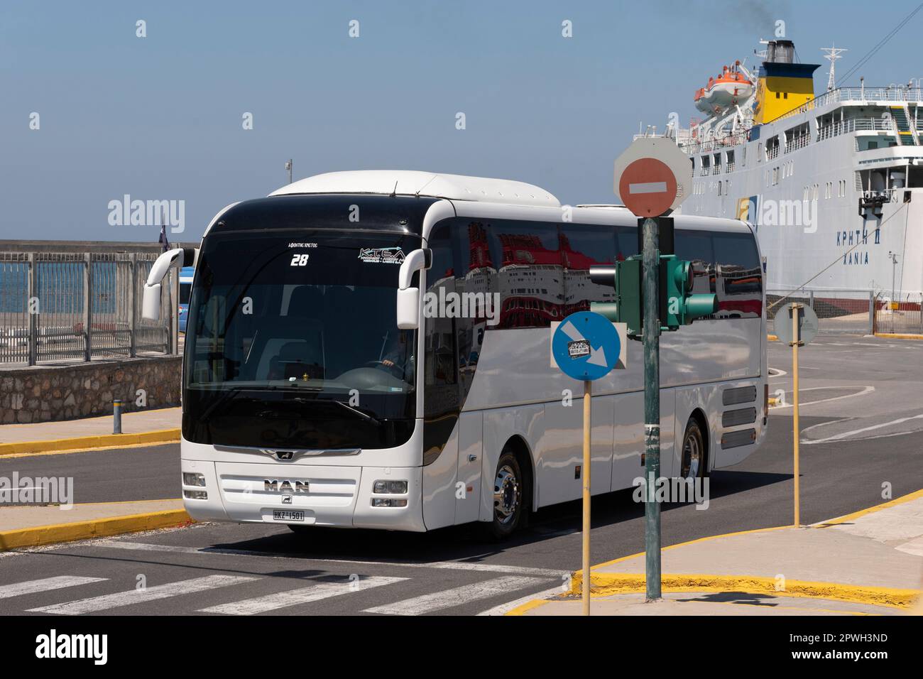 Heraklion, Kreta, Griechenland, EU. 2023. Weißer Tourbus, der den Hafen von Heraklion im Hintergrund mit einer Inselfähre verlässt. Stockfoto