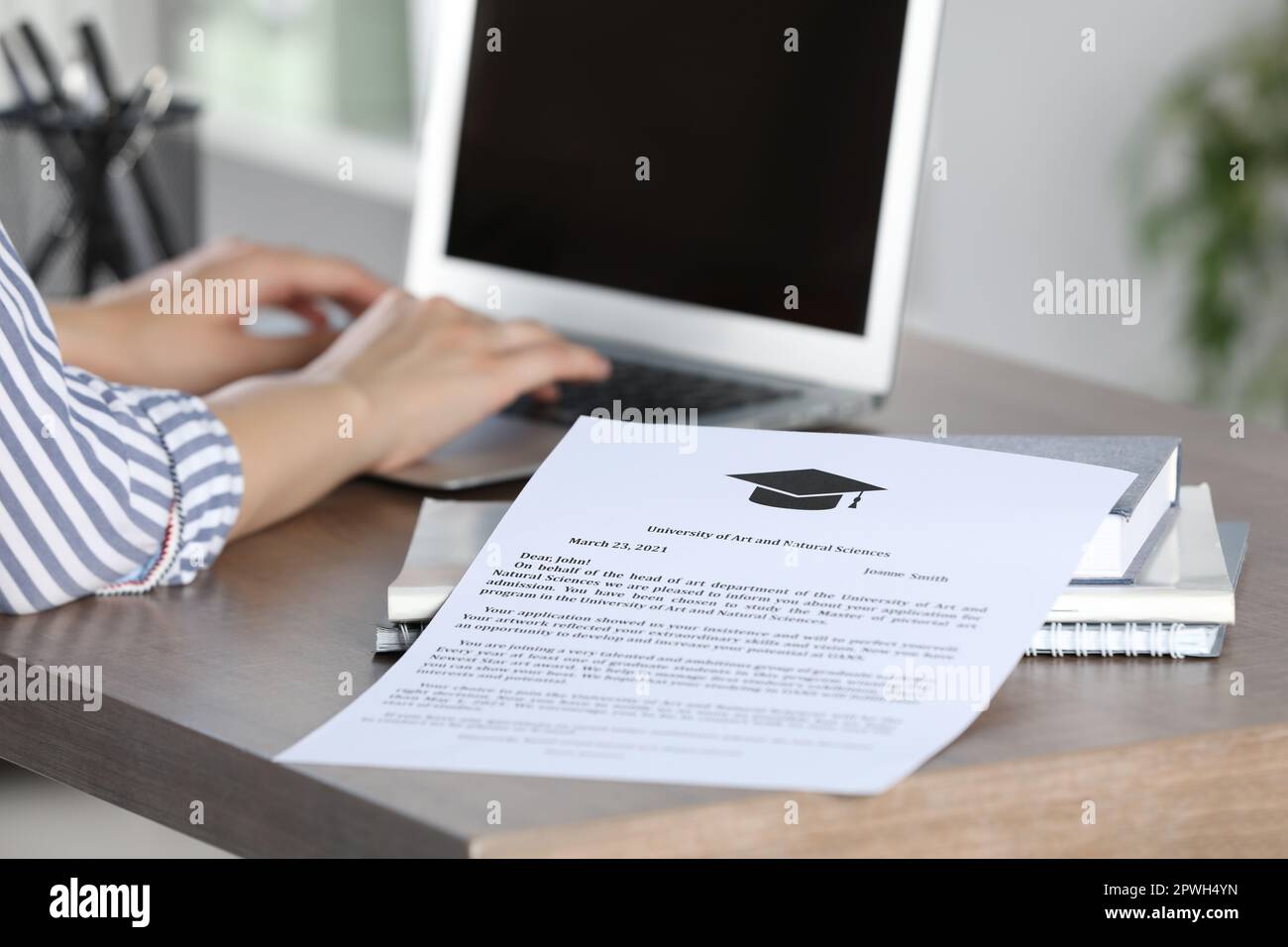 Schüler, die mit einem Laptop an einem Tisch im Innenbereich arbeiten, konzentrieren sich auf das Akzeptanzschreiben der Universität Stockfoto