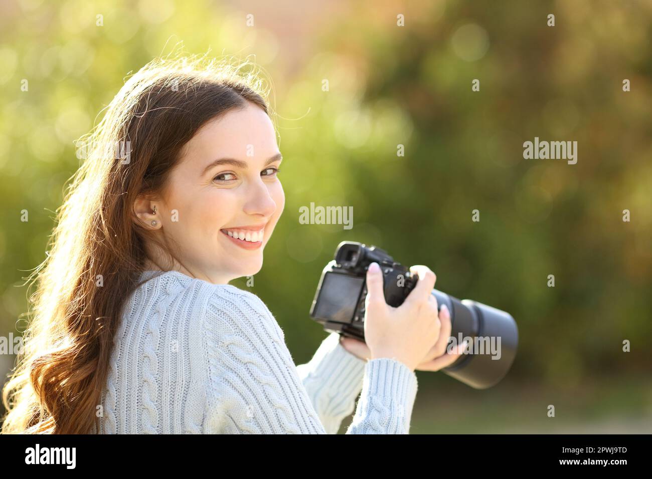 Ein glücklicher Fotograf im Park sieht dich mit der Kamera an Stockfoto