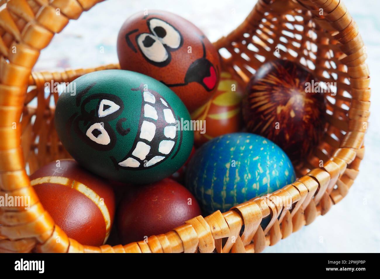 Ostereier in verschiedenen Farben mit gemalten, lachenden Gesichtern. Lustige Grimassen mit Augen, Zunge und großen weißen Zähnen. Unheimliches Gesicht für Halloween. Em Stockfoto