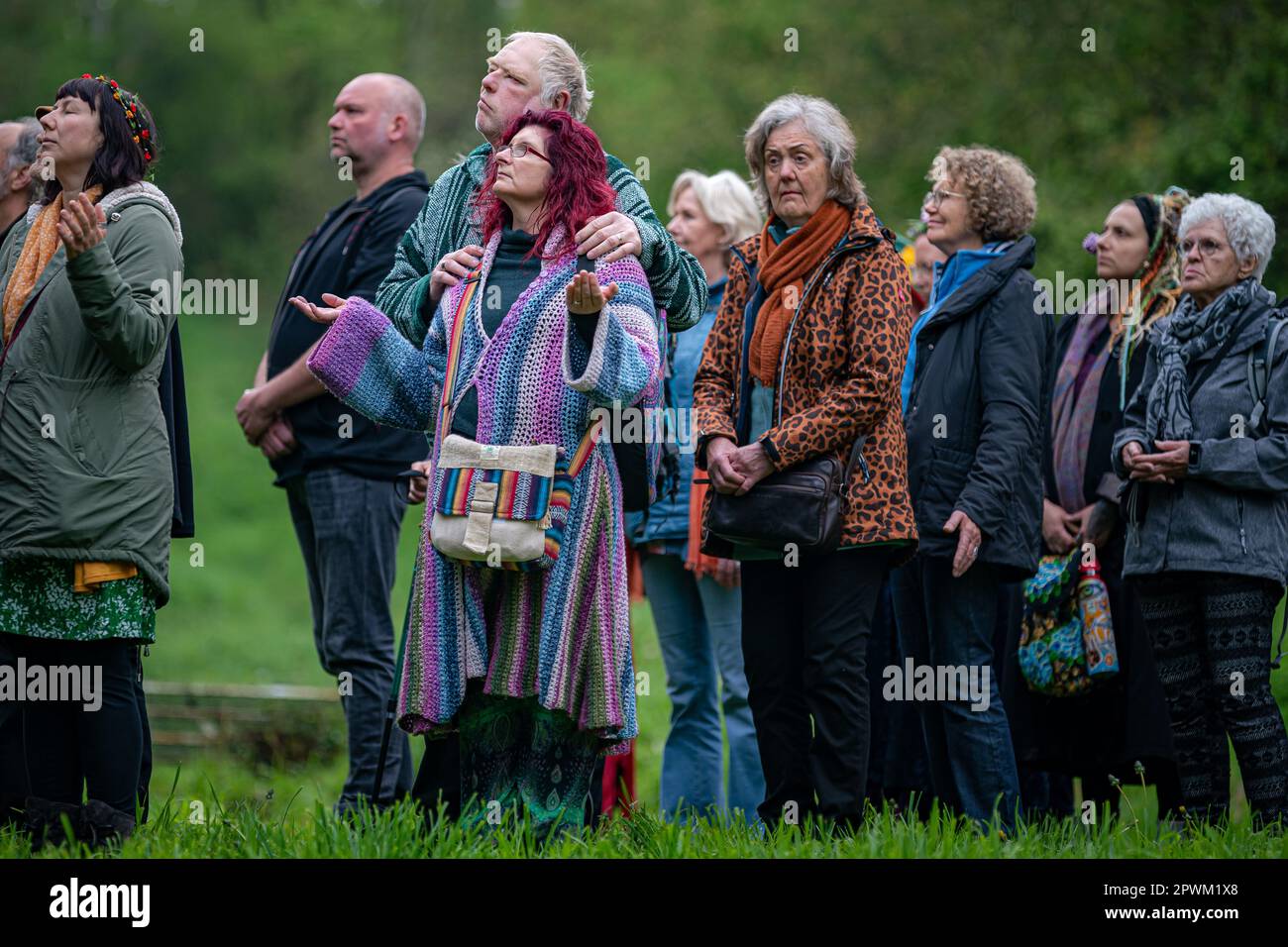 Die Menschen beobachten die Beltane-Zeremonie in Chalice Well, Glastonbury, Somerset, wo Beltane bei Sonnenaufgang und den ganzen Tag über gefeiert wird. Foto: Montag, 1. Mai 2023. Das Wort Beltane wird grob als „helles Feuer“ übersetzt und ist ein wichtiges Ritual, das heute als gälische Tradition überlebt, wo ein Beltane-Lagerfeuer angezündet wird. Als Reinigungs- und Heiler hätten die Menschen laufen, getanzt und über das Feuer gesprungen, während die Bauern ihre Rinder auch zwischen Lagerfeuer getrieben hätten, um sie zu reinigen und zu schützen, bevor sie auf die Felder gebracht wurden. Stockfoto