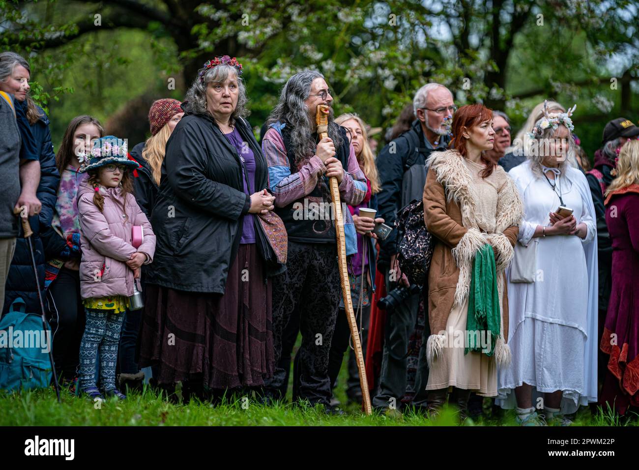 Die Menschen beobachten die Beltane-Zeremonie in Chalice Well, Glastonbury, Somerset, wo Beltane bei Sonnenaufgang und den ganzen Tag über gefeiert wird. Foto: Montag, 1. Mai 2023. Das Wort Beltane wird grob als „helles Feuer“ übersetzt und ist ein wichtiges Ritual, das heute als gälische Tradition überlebt, wo ein Beltane-Lagerfeuer angezündet wird. Als Reinigungs- und Heiler hätten die Menschen laufen, getanzt und über das Feuer gesprungen, während die Bauern ihre Rinder auch zwischen Lagerfeuer getrieben hätten, um sie zu reinigen und zu schützen, bevor sie auf die Felder gebracht wurden. Stockfoto