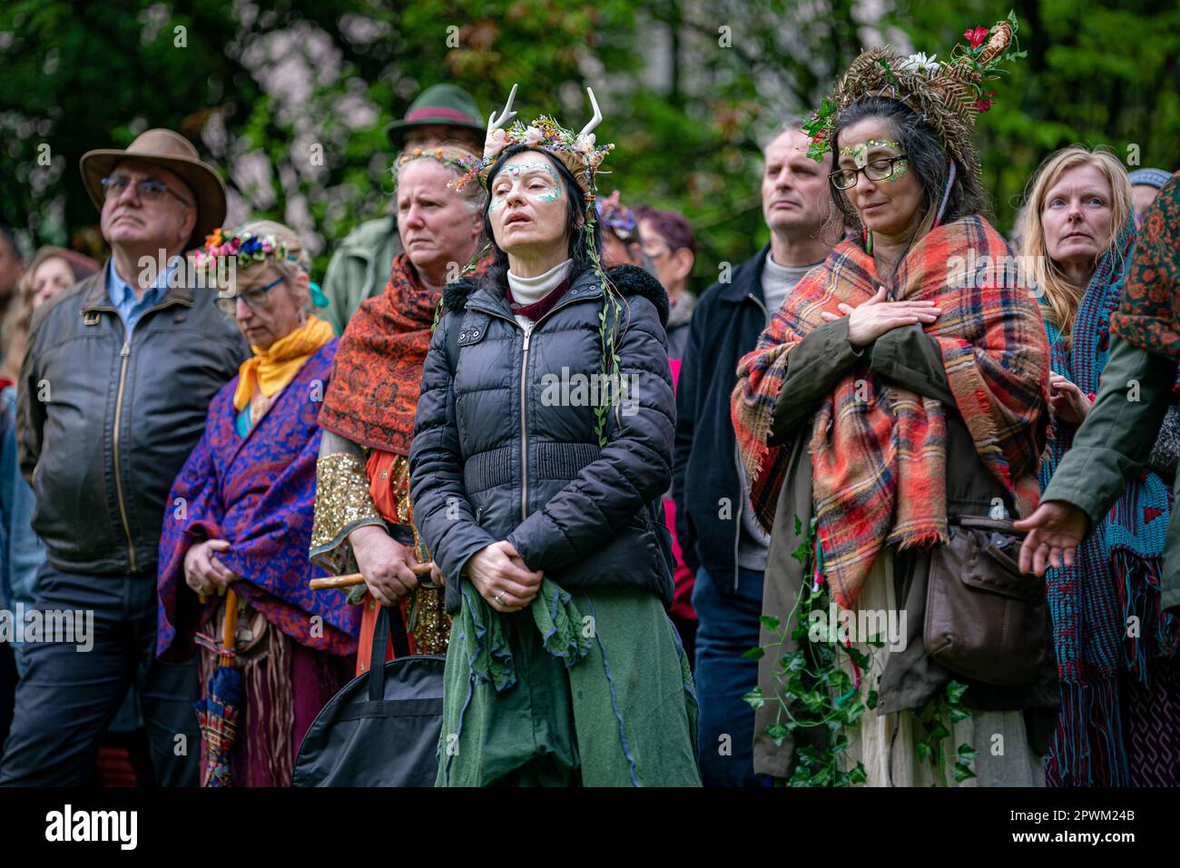 Die Menschen beobachten die Beltane-Zeremonie in Chalice Well, Glastonbury, Somerset, wo Beltane bei Sonnenaufgang und den ganzen Tag über gefeiert wird. Foto: Montag, 1. Mai 2023. Das Wort Beltane wird grob als „helles Feuer“ übersetzt und ist ein wichtiges Ritual, das heute als gälische Tradition überlebt, wo ein Beltane-Lagerfeuer angezündet wird. Als Reinigungs- und Heiler hätten die Menschen laufen, getanzt und über das Feuer gesprungen, während die Bauern ihre Rinder auch zwischen Lagerfeuer getrieben hätten, um sie zu reinigen und zu schützen, bevor sie auf die Felder gebracht wurden. Stockfoto