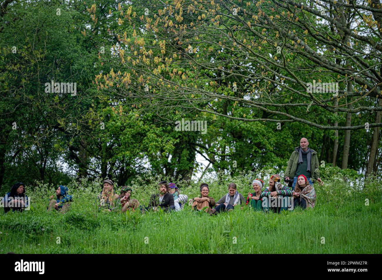 Die Menschen beobachten die Beltane-Zeremonie in Chalice Well, Glastonbury, Somerset, wo Beltane bei Sonnenaufgang und den ganzen Tag über gefeiert wird. Foto: Montag, 1. Mai 2023. Das Wort Beltane wird grob als „helles Feuer“ übersetzt und ist ein wichtiges Ritual, das heute als gälische Tradition überlebt, wo ein Beltane-Lagerfeuer angezündet wird. Als Reinigungs- und Heiler hätten die Menschen laufen, getanzt und über das Feuer gesprungen, während die Bauern ihre Rinder auch zwischen Lagerfeuer getrieben hätten, um sie zu reinigen und zu schützen, bevor sie auf die Felder gebracht wurden. Stockfoto