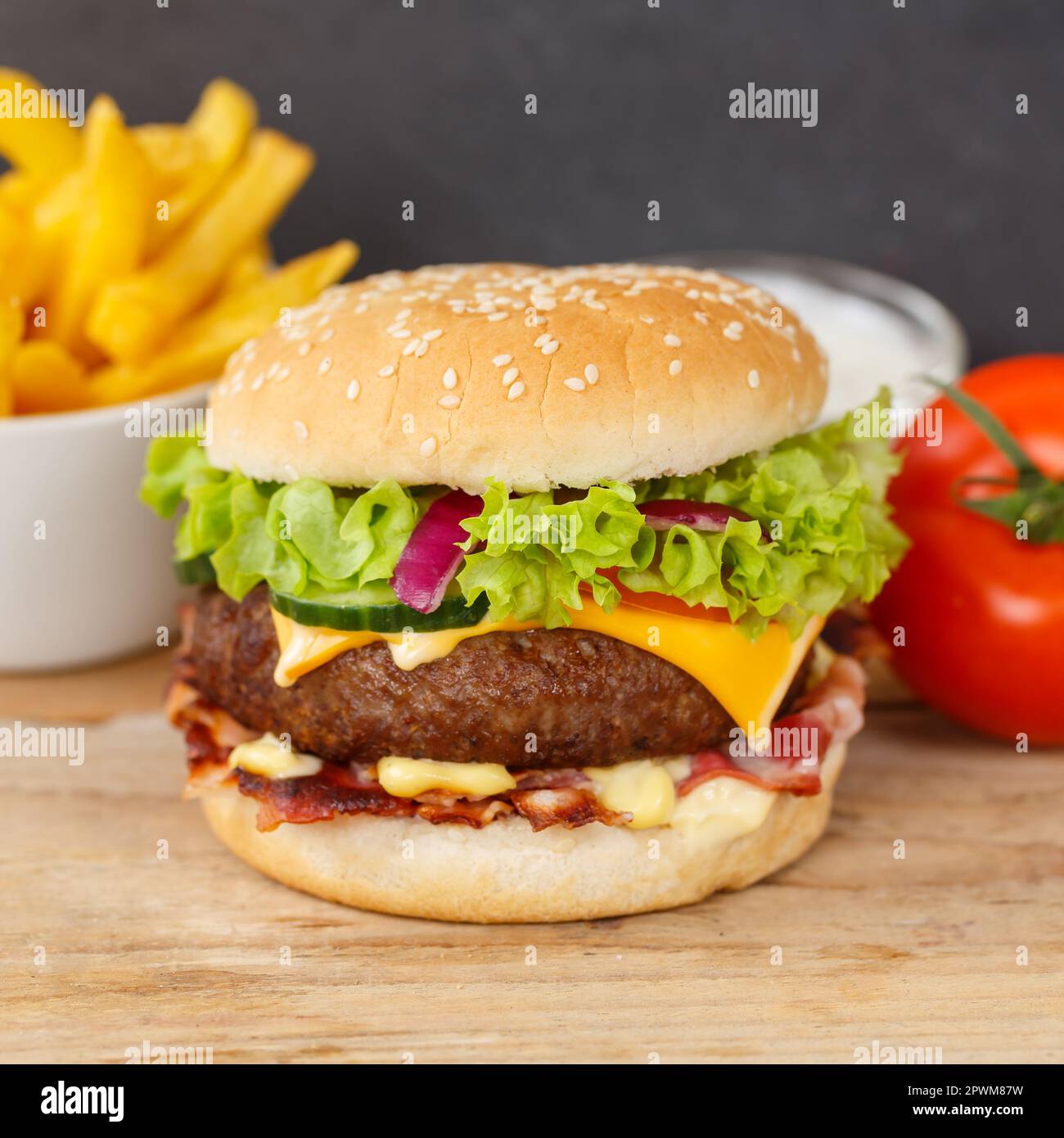 Hamburger Cheeseburger Mahlzeit Fast Food mit Pommes auf einem quadratischen Snack aus Holzbrett Stockfoto