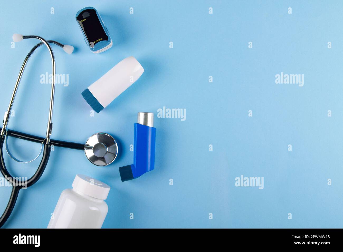 Draufsicht von Stethoskop, Oxymeter, Flasche Pillen und Inhalatoren auf blauem Hintergrund mit Kopierbereich. Konzept der Atembeschwerden durch Asthma Stockfoto