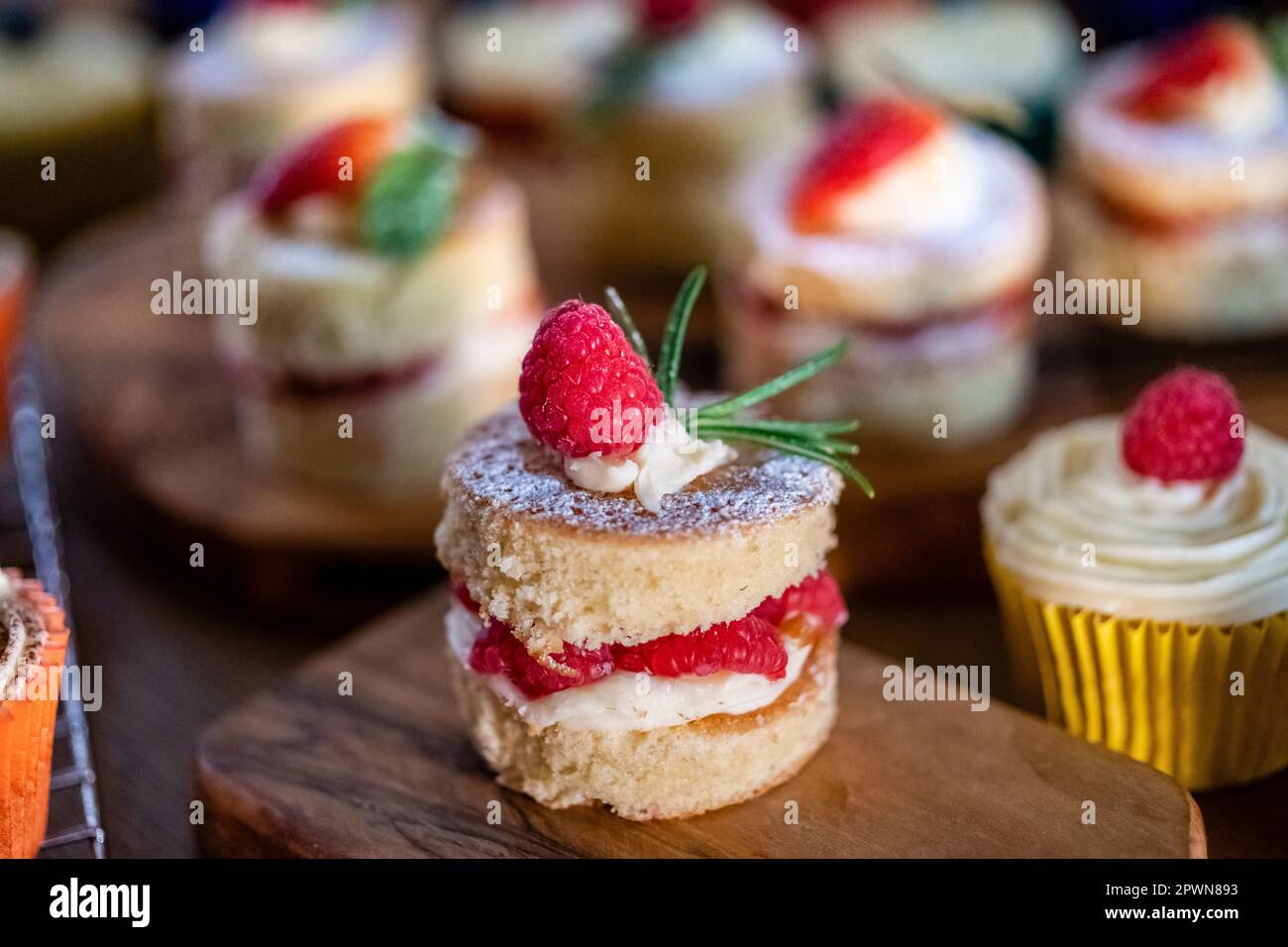 Wunderschöne Mini-Viktoriaschwämme, frische Früchte Himbeeren Erdbeeren gefüllt mit Buttercreme und Obst Stockfoto