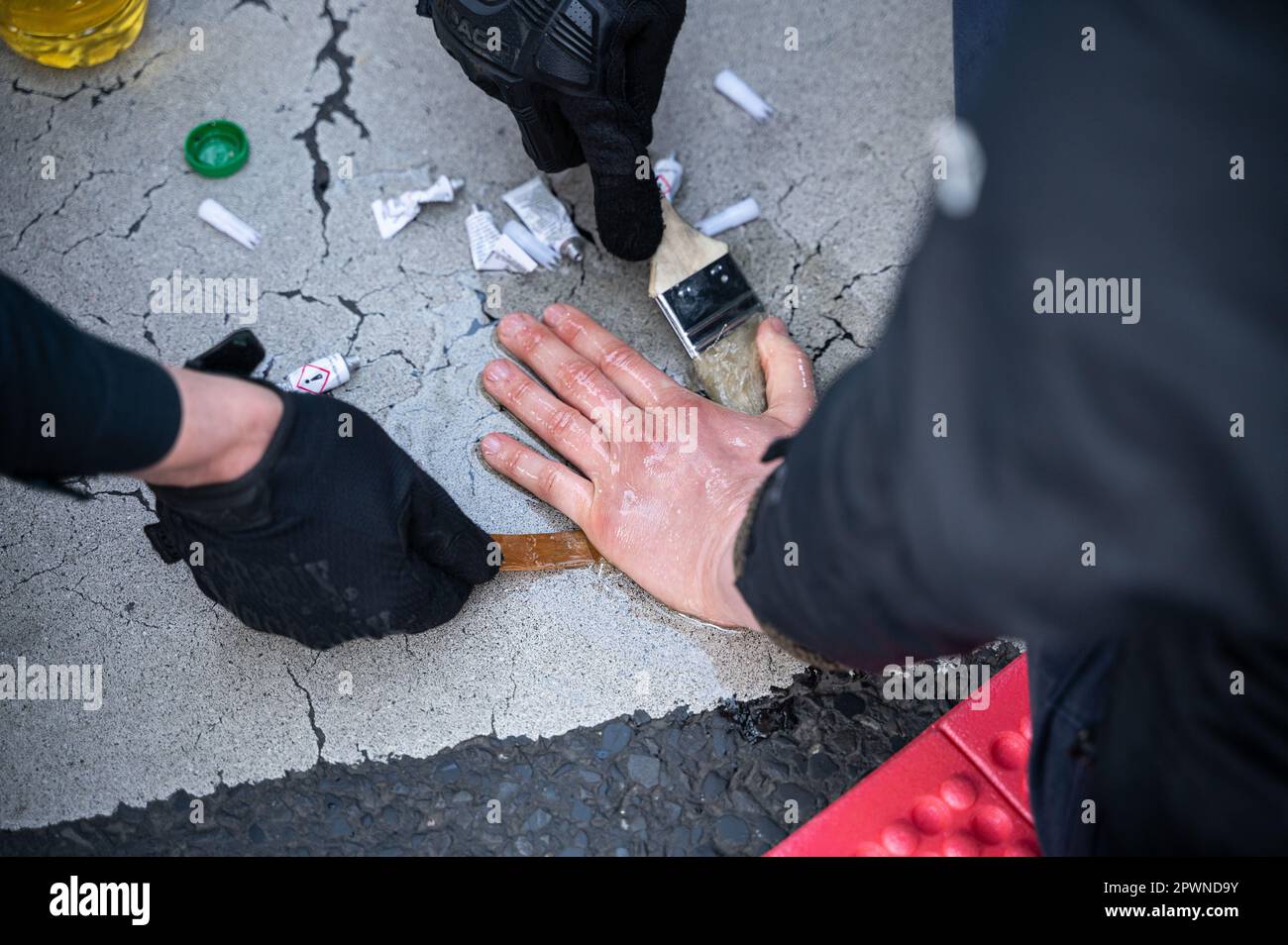 28.04.2023, Berlin, Deutschland, Europa - mit Speiseöl lockern Polizeibeamte die Hand von Klimaprotestierenden der letzten Generation. Stockfoto