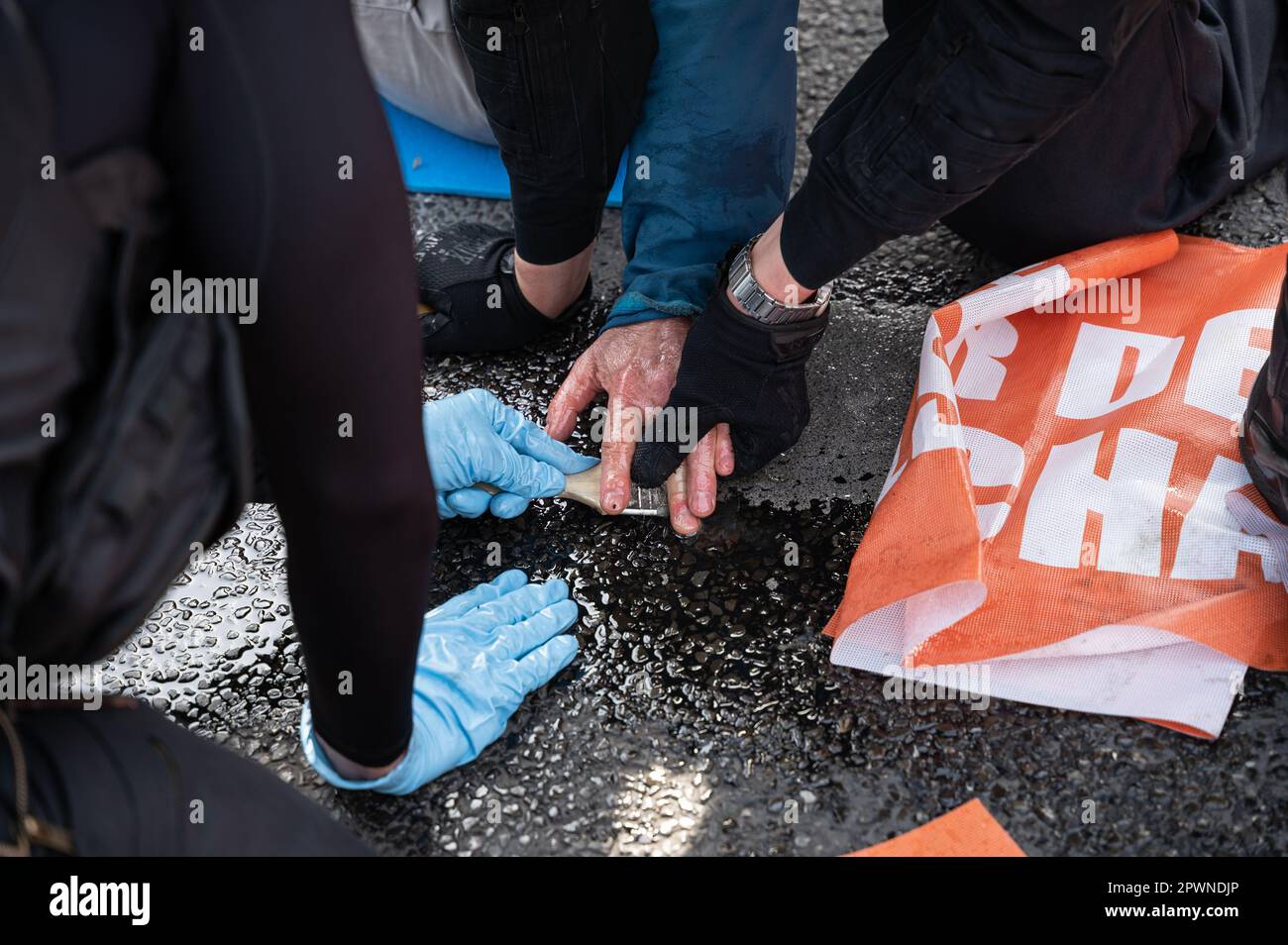 28.04.2023, Berlin, Deutschland, Europa - mit Speiseöl lockern Polizeibeamte die Hand von Klimaprotestierenden der letzten Generation. Stockfoto