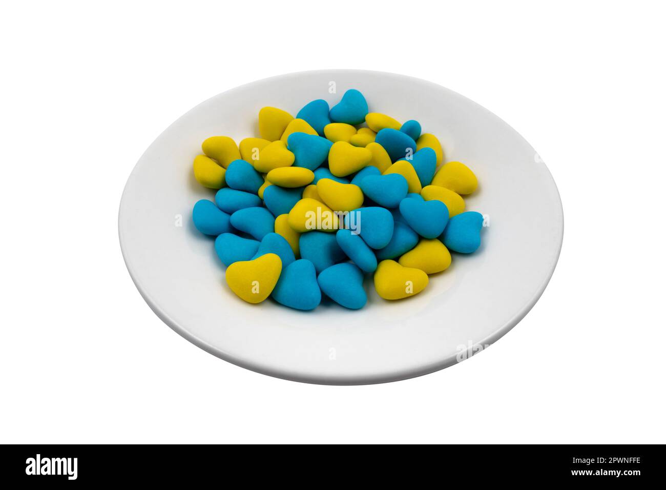Weiße Platte mit blauen und gelben herzförmigen Süßigkeiten (Nahaufnahme), isoliert auf weißem Hintergrund. Staatssymbole der Ukraine. Blick von oben Stockfoto