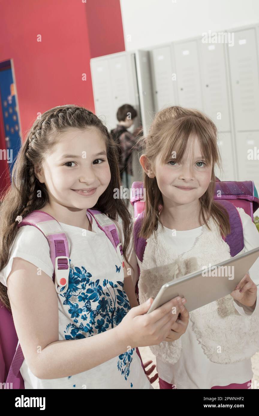 Zwei Schulmädchen mit einem digitalen Tablet im Flur in der Nähe von Schließfächern, Bayern, Deutschland Stockfoto