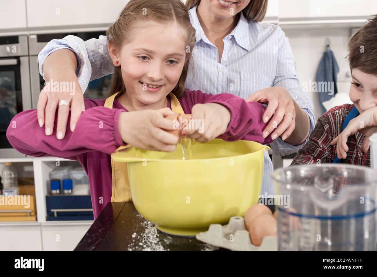 Ein Schulmädchen, das ein Ei in eine Mischschüssel knackt, in der Hauswirtschaftsschule, Bayern, Deutschland Stockfoto