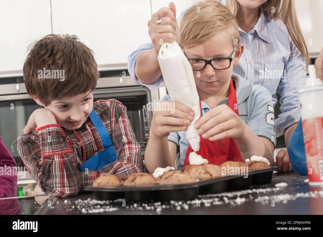 Schülerjucken auf Muffins mit Eisbeutel im Hauswirtschaftskurs, Bayern, Deutschland Stockfoto