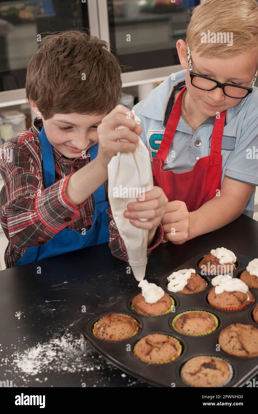 Schülerjucken auf Muffins mit Eisbeutel im Hauswirtschaftskurs, Bayern, Deutschland Stockfoto