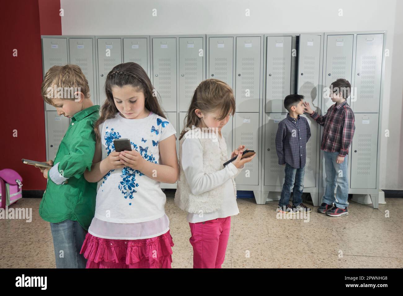 Schulkinder mit Smartphone im Korridor in der Nähe von Schließfächern, Bayern, Deutschland Stockfoto