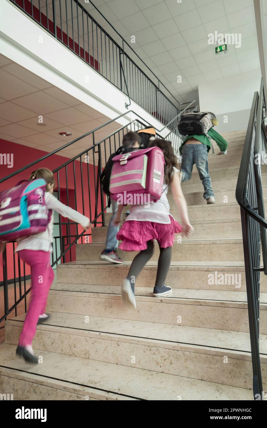 Rückansicht von Schülern, die die Treppe hinauflaufen, Bayern, Deutschland Stockfoto