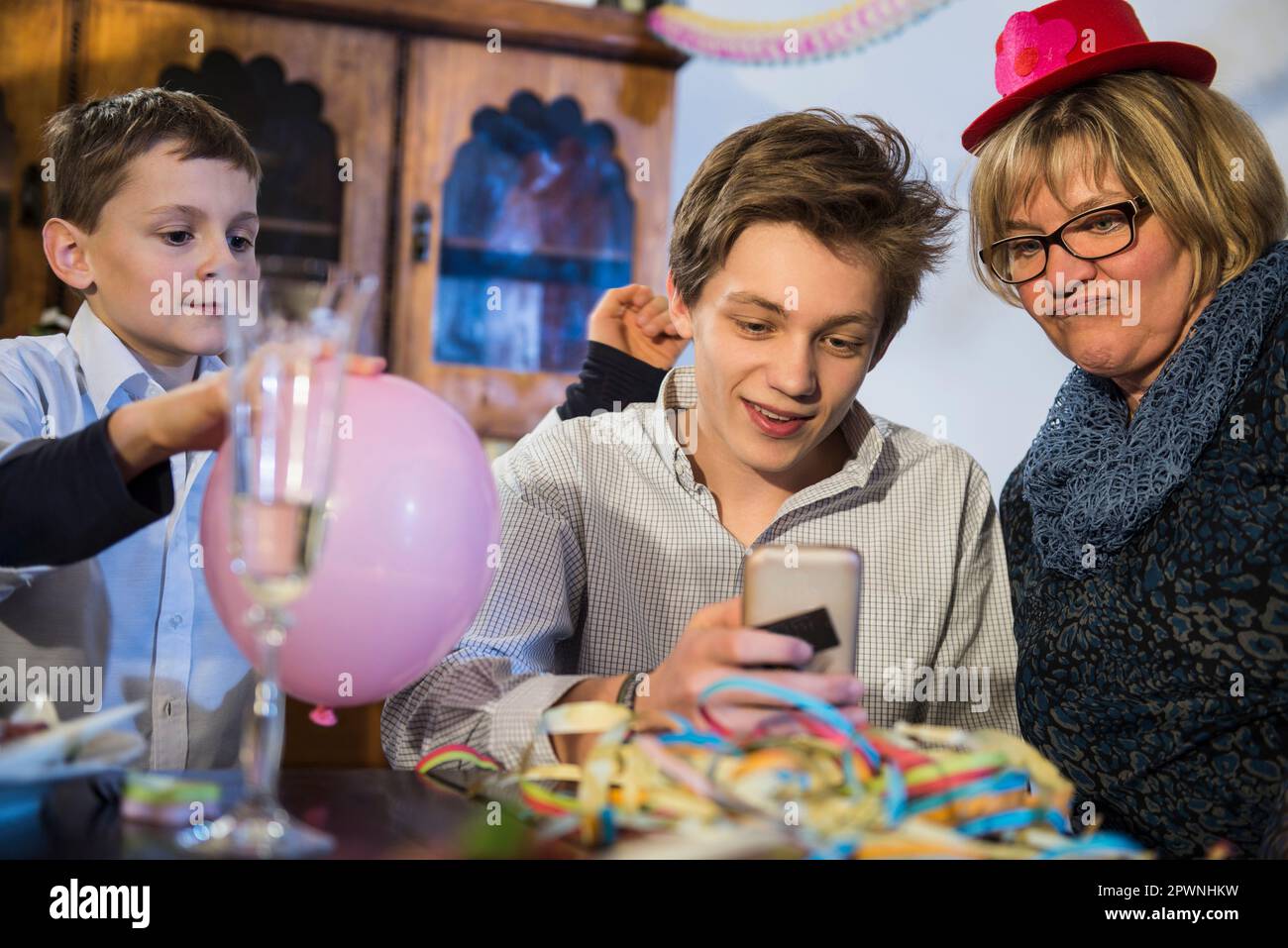 Teenager mit Großmutter, der auf einer Party ein Smartphone benutzt Stockfoto