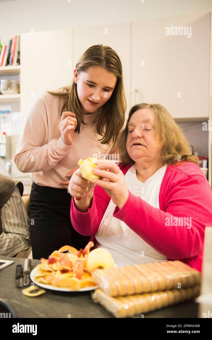 Seniorin mit einem Mädchen, das Apfel schneidet Stockfoto