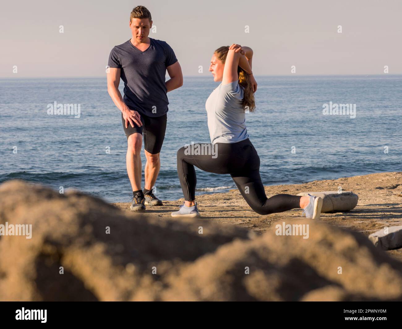 Mann und Frau, die sich am Strand von Azkorri strecken Stockfoto