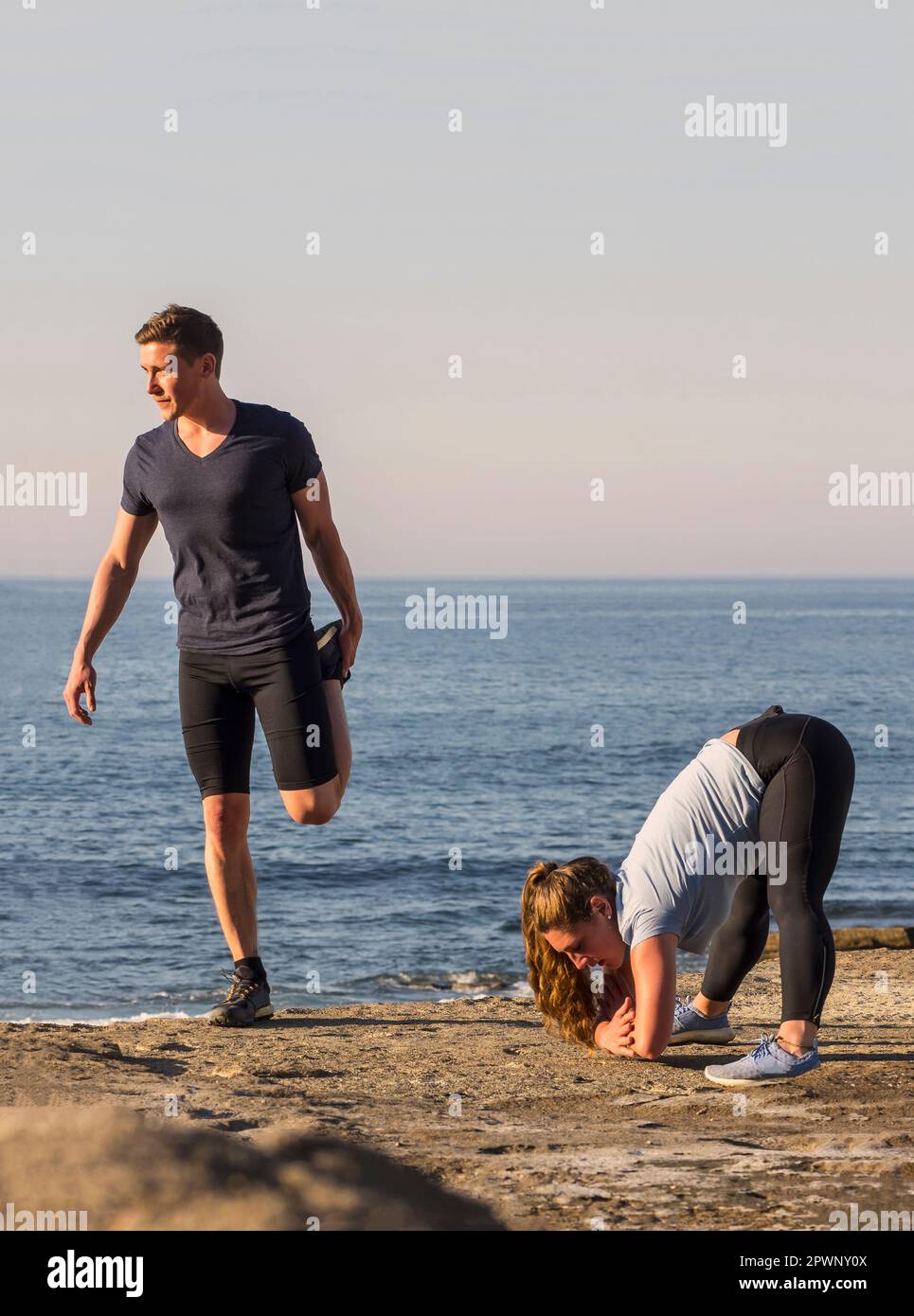 Mann und Frau, die sich am Strand von Azkorri strecken Stockfoto