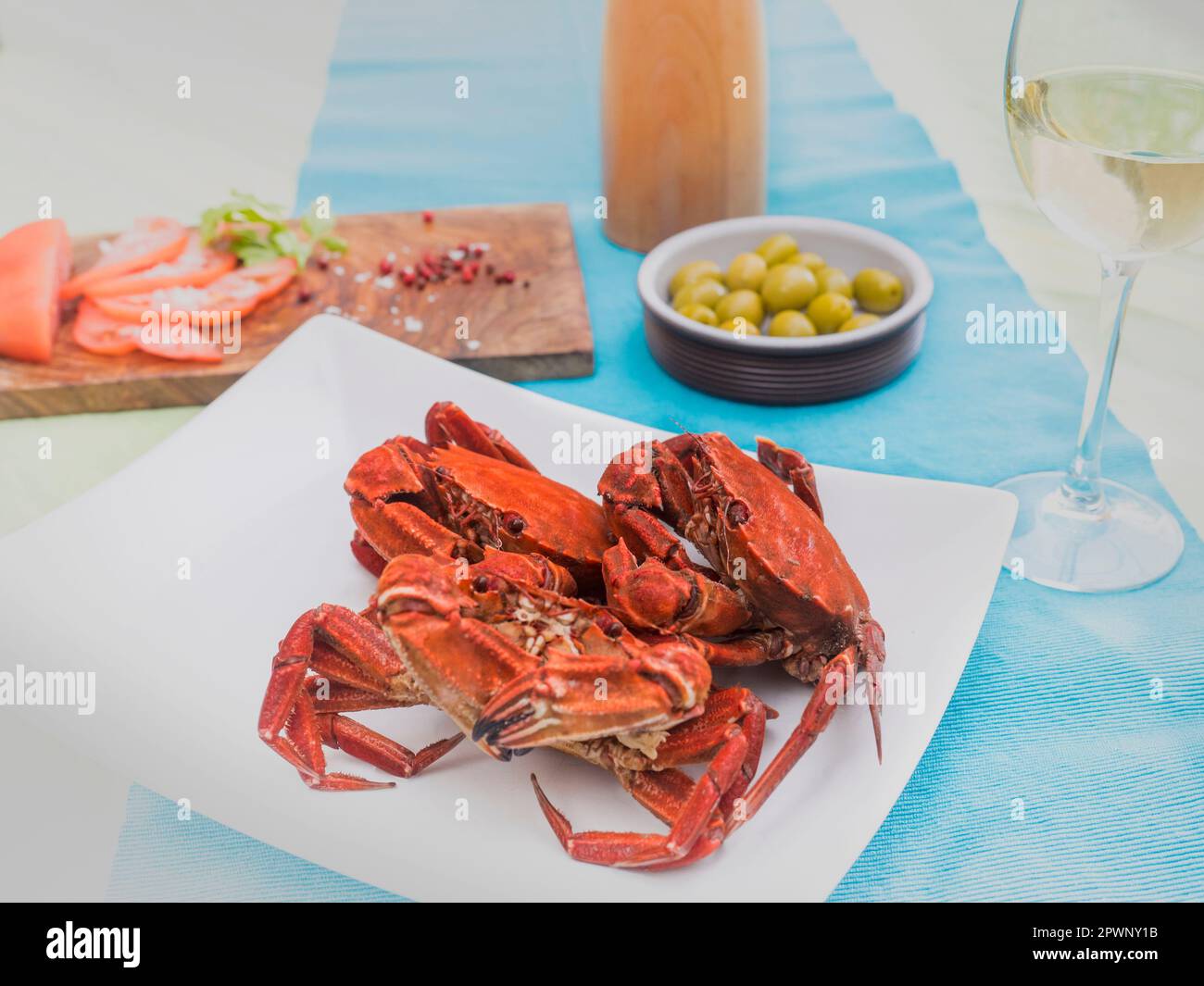 Gekochte Samtkrabben, serviert mit Weißwein, Tomaten und Oliven Stockfoto