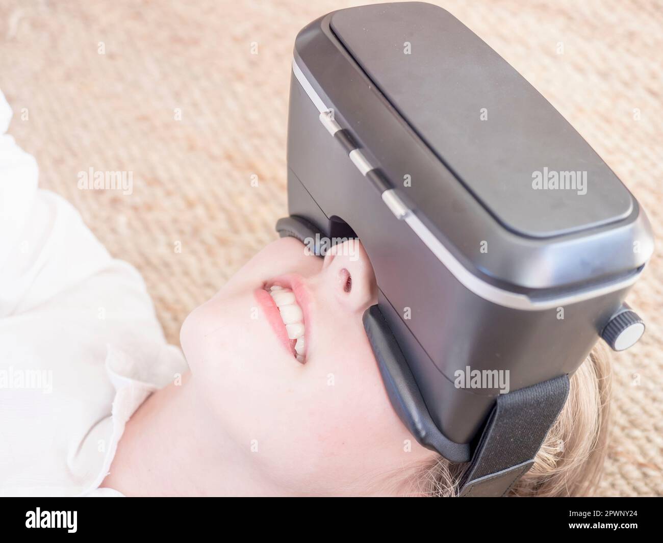 Mädchen, die ein Virtual-Reality-Headset verwendet, während sie auf dem Boden liegt Stockfoto