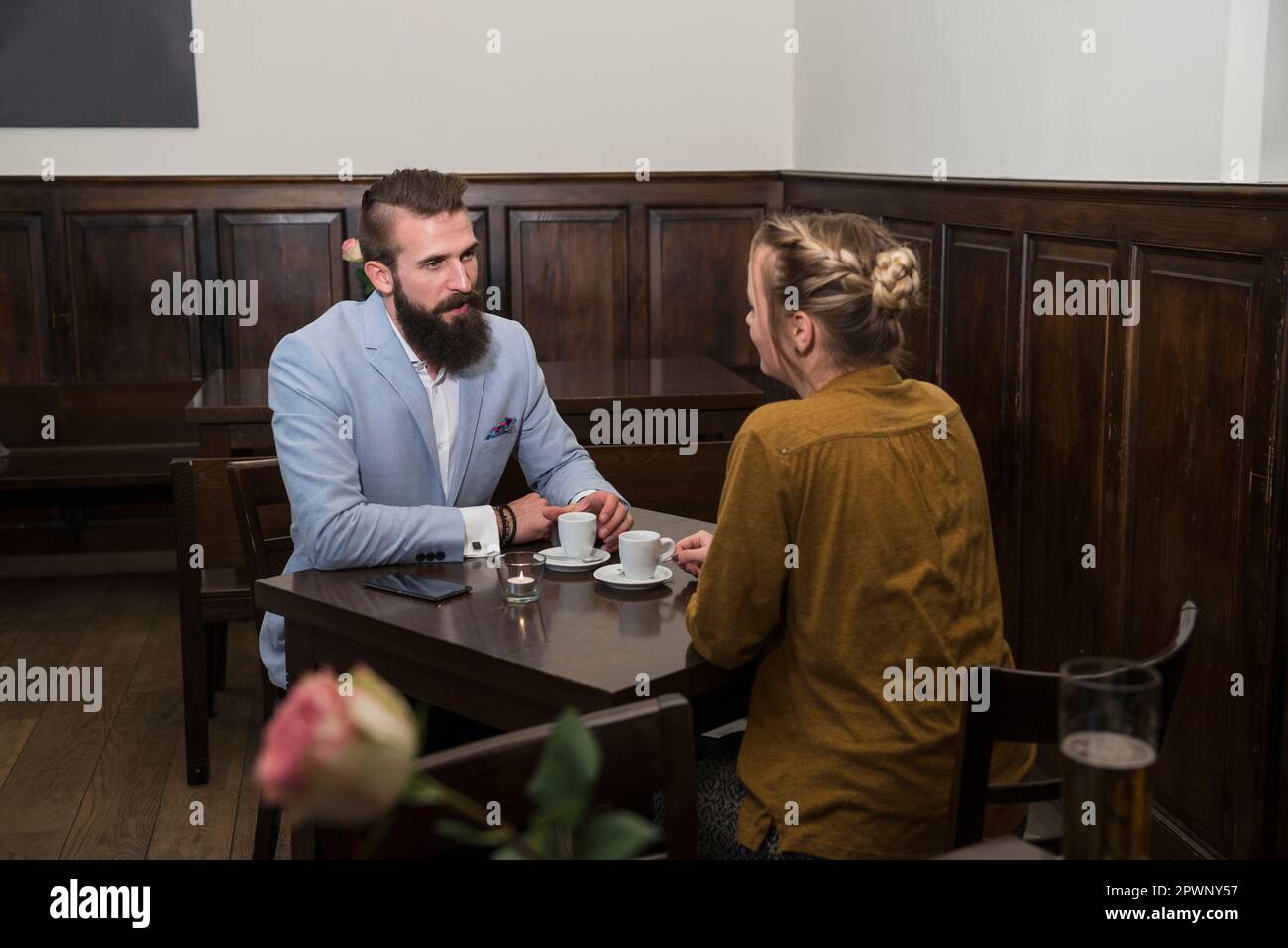 Ein junges Paar, das sich im Restaurant unterhält, während es mit einer Kaffeetasse am Esstisch sitzt Stockfoto