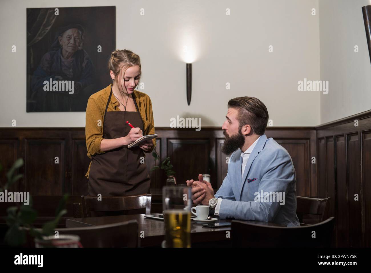 Kellnerin nimmt Bestellung vom Gast im Restaurant entgegen Stockfoto