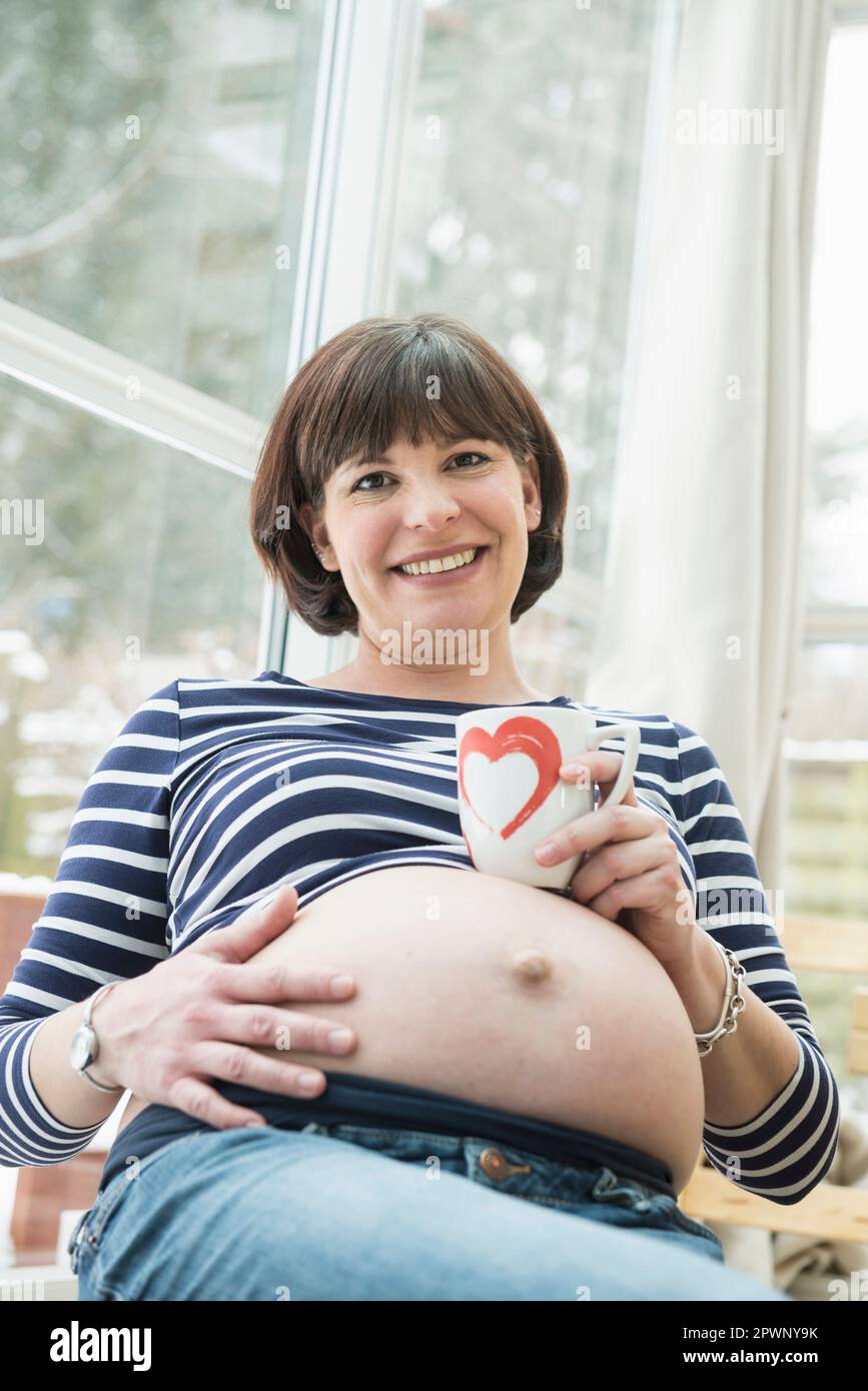 Porträt einer schwangeren Frau mit Kaffeetasse Stockfoto
