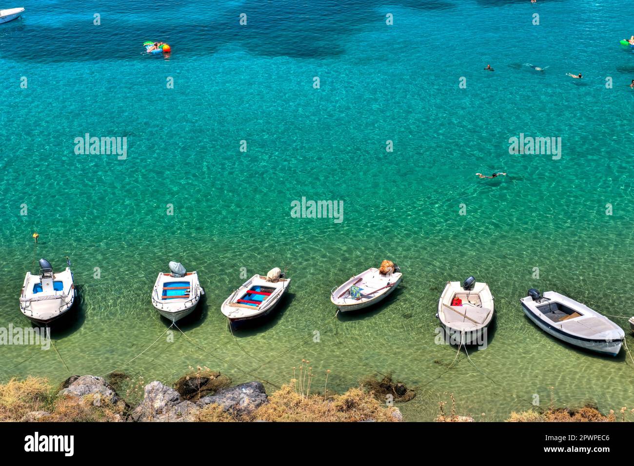 Weiße Boote liegen am Ufer des Meeres mit klarem türkisfarbenem Wasser vor Anker Stockfoto