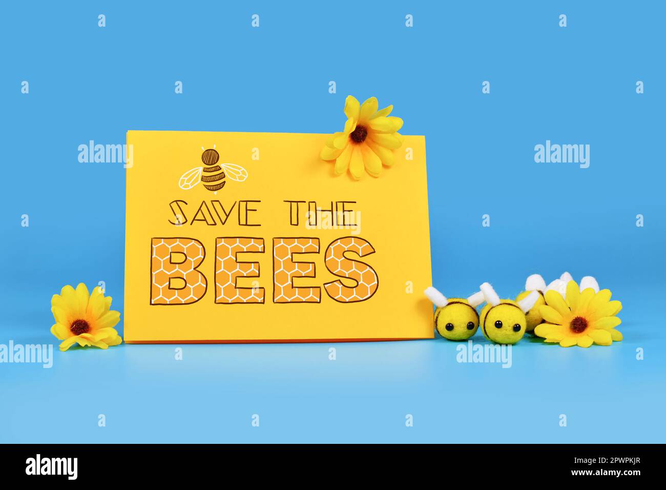 Das Schild "Rettet die Bienen" mit Filzbienen und gelben Blumen Stockfoto