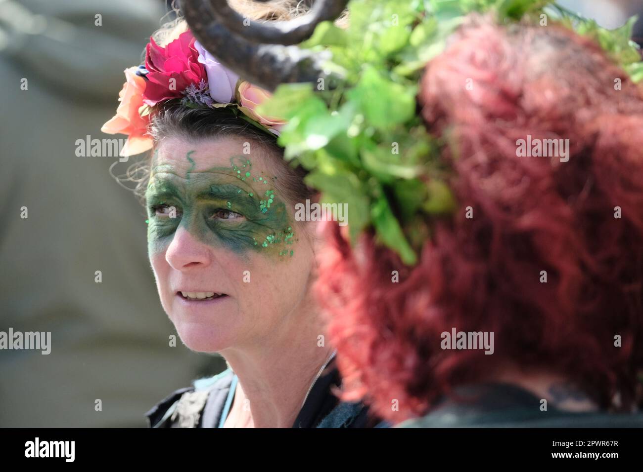 Glastonbury, Somerset, Großbritannien. 1. Mai 2023 Dekorierte Gesichter in der Menge. Die heidnischen Beltane-Feierlichkeiten finden jedes Jahr zwischen dem Frühling und dem Sommerfrühstück am 1. Mai statt. Die Leute treffen sich, ziehen sich grün an, genießen eine Parade, Musik und Tanz. Das Festival hat seine Wurzeln in den frühen gälischen Saisonfeiern und passt gut zu der neuen Altersgemeinschaft, die diese kleine Stadt Somerset anzieht. Sie versammeln sich am Marktkreuz in der Stadt, der Maimast wird dem Maikönig und der Maikönigin übergeben, die zusammen mit den Grünen den Maimast zum Kelchbrunnen tragen. Kredit: Herr Standfast/Alamy Live N. Stockfoto