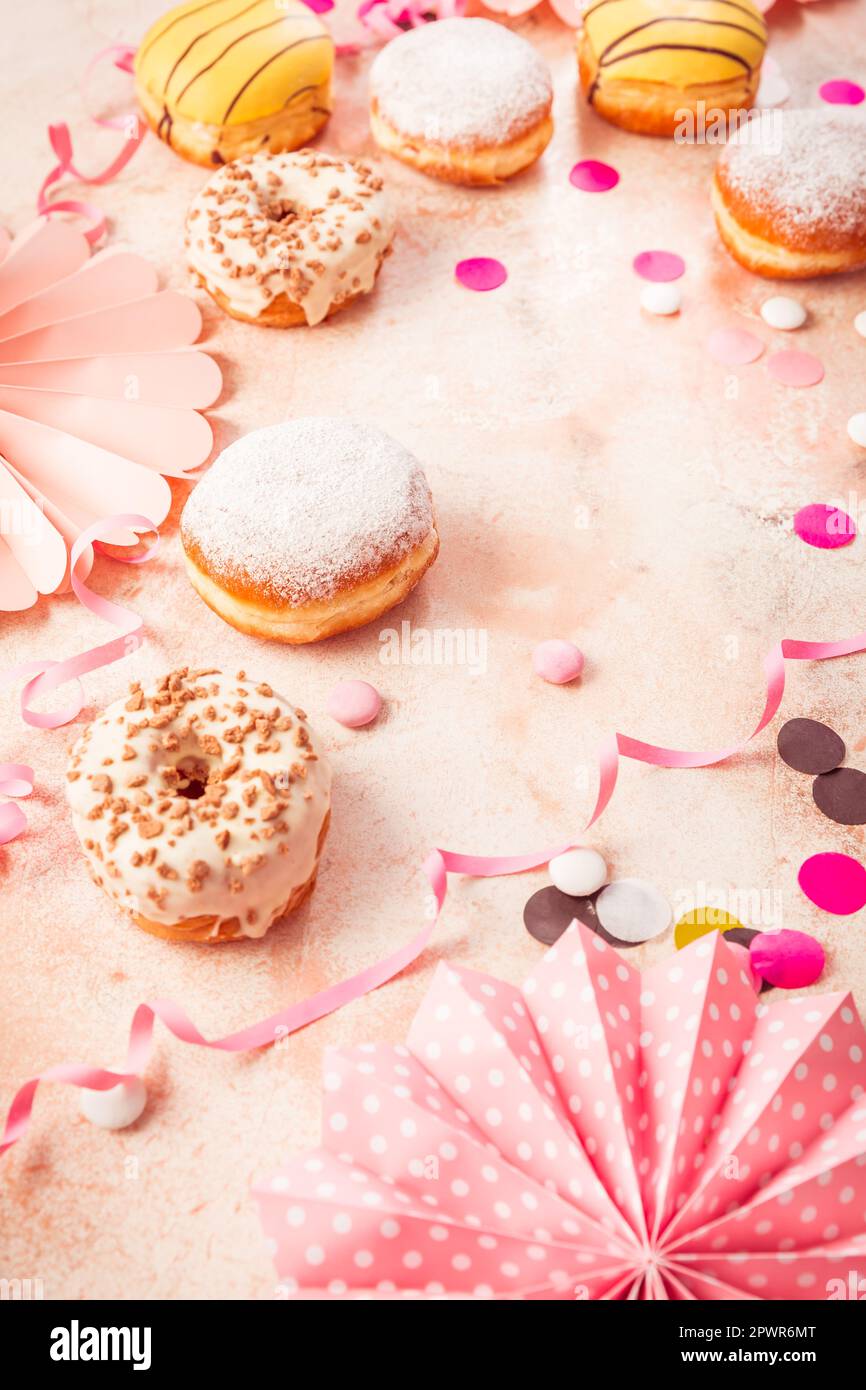 Traditioneller Berliner für Fasching und Party. Deutsch Krapfen oder Donuts mit Streamer und Konfetti. Bunte Karneval oder Geburtstag Bild Stockfoto