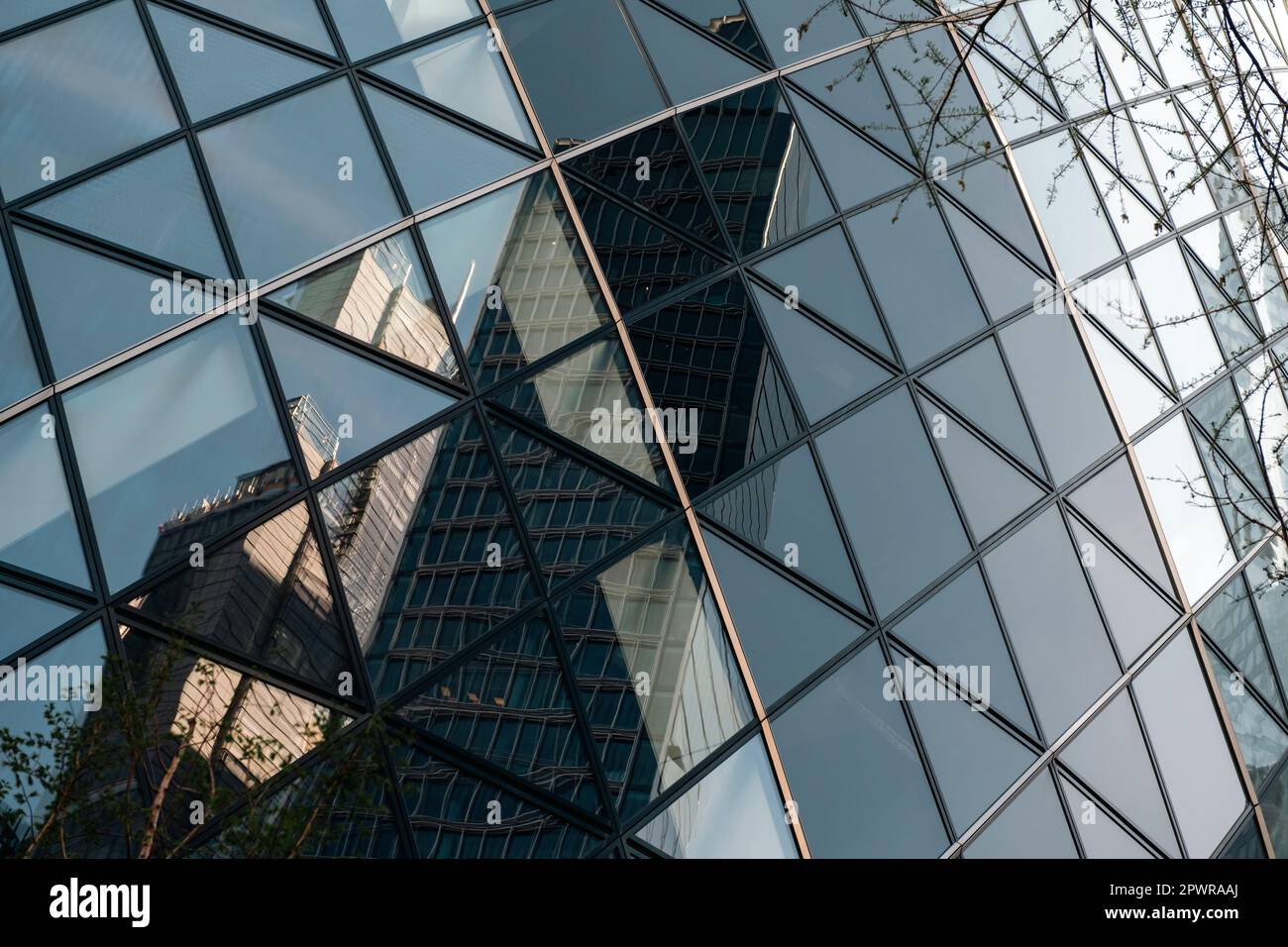 Nahaufnahme des Gherkin-Gebäudes in der Stadt london. Die Glasscheiben erscheinen gekrümmt, sind es aber nicht. Gebäude werden reflektiert. Stockfoto